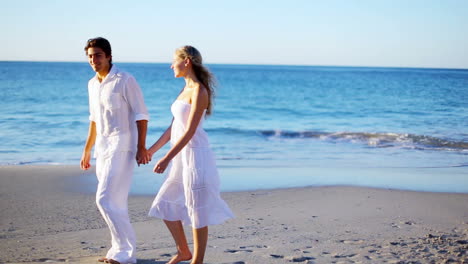 Couple-holding-hands-while-walking-along-the-beach