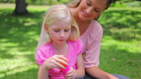 A-girl-repeatedly-blows-bubbles-with-her-mother-as-she-sits-in-the-park