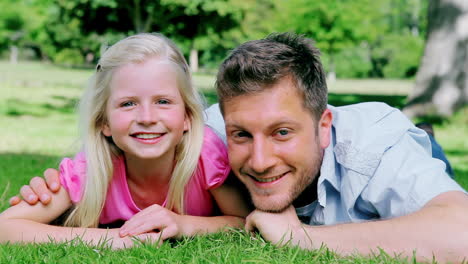 Man-looks-at-his-daughter-with-a-confused-look-before-smiling-as-they-lie-on-the-grass