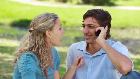Man-talks-on-a-phone-as-he-passes-the-phone-over-to-his-girfriend