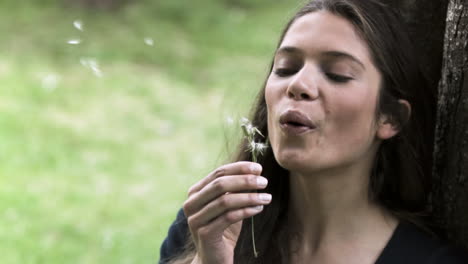 Relaxed-woman-in-slow-motion-blowing-a-dandelion