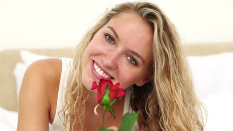 Blonde-haired-woman-smelling-a-red-rose