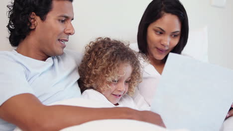 Family-with-a-book-sitting-on-their-bed