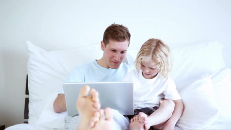 Padre-E-Hijo-Sonrientes-Mirando-Una-Computadora-Portátil