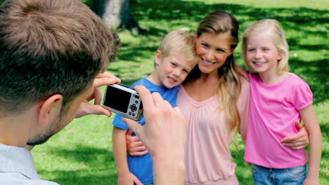 A-man-points-a-camera-at-his-family-who-hold-each-other-before-they-turn-to-the-camera-and-smile
