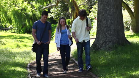 Three-students-talking-to-each-other-as-they-walk-on-a-park-trail