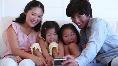 Familia-Sentada-Juntos-Mientras-Posan-Para-Una-Fotografía