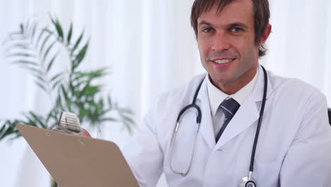 Doctor-writing-on-a-clipboard-while-sitting