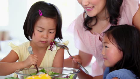 Daughters-mixing-a-salad-with-their-mother