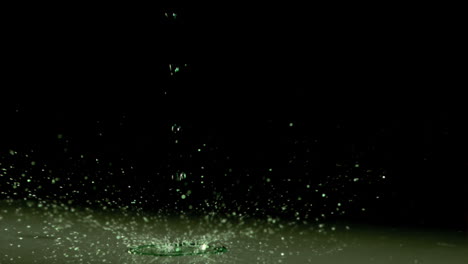 Liquid-dripping-in-super-slow-motion-under-green-light