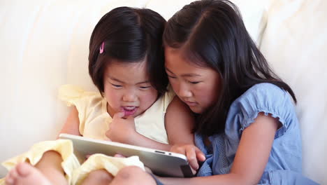 Two-girls-laughing-while-using-a-tablet-computer