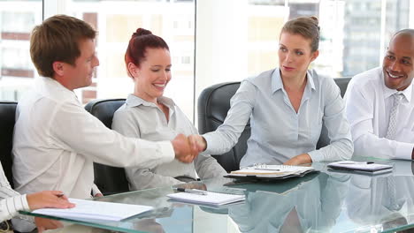 Business-group-in-an-office-with-two-shaking-hands