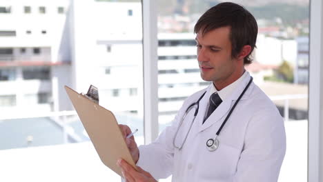 Doctor-writing-on-a-clipboard-while-standing