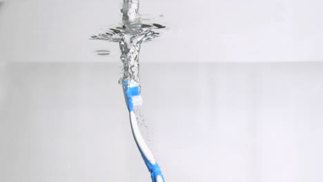 Eine-Blaue-Zahnbürste-Fällt-In-Superzeitlupe-Senkrecht-Ins-Wasser-