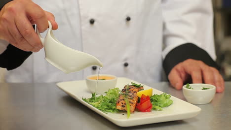 Cook-pouring-dressing-over-salmon-and-salad