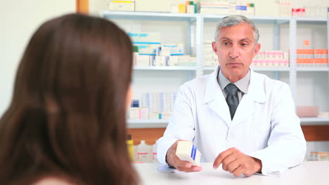 Pharmacist-talking-to-a-customer-while-holding-a-box-of-pills