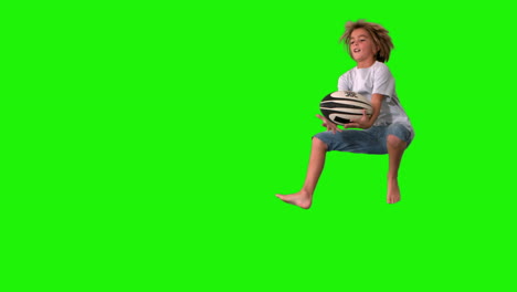 Boy-jumping-up-to-catch-rugby-ball-on-green-screen