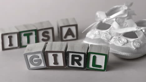 Its-a-girl-message-in-letter-blocks-beside-booties