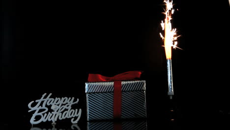 Sparkler-burning-beside-gift-and-happy-birthday-sign