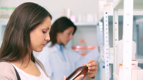 Female-client-holding-a-paper-and-pills-while-standing-in-a-pharmacy