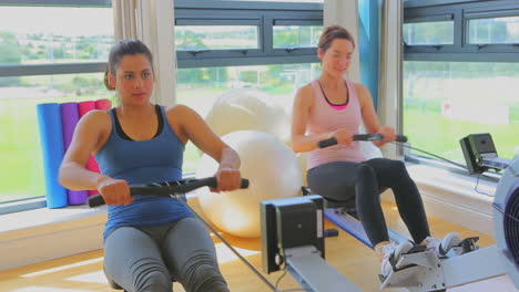 Women-at-the-rowing-machine-supporting-by-a-coach-