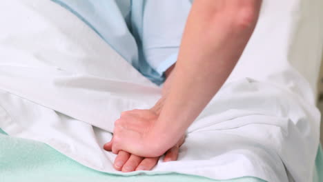 Woman-lying-on-a-bed-while-talking-to-a-nurse