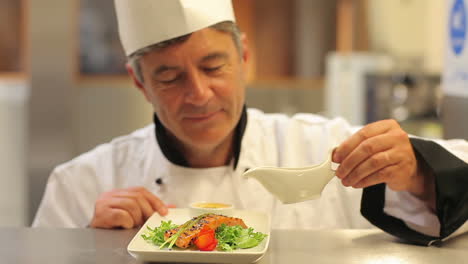 Smiling-chef-pouring-dressing-over-salmon-dish