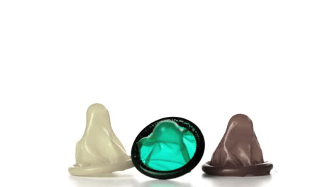 Three-condoms-falling-on-white-background