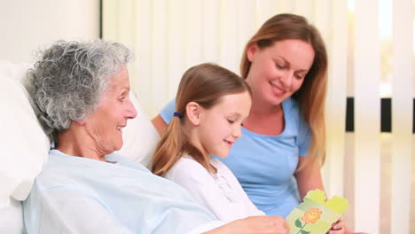 Mujer-Sonriente-Y-Niña-Sentada-En-La-Cama-De-Un-Paciente