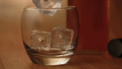 Tongs-placing-ice-into-tumbler-and-whiskey-being-poured-