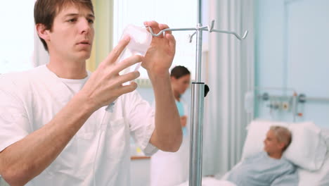 Male-nurse-placing-a-bag-on-a-drip-stand