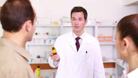 Pharmacist-presenting-a-flask-of-pills-to-a-couple