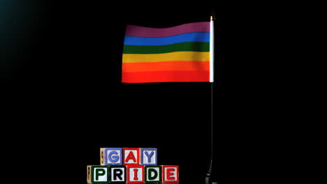 Bandera-Del-Arco-Iris-Ondeando-En-La-Brisa-Al-Lado-De-Bloques-Del-Orgullo-Gay-Sobre-Fondo-Negro