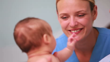 Madre-Sonriente-Sosteniendo-A-Un-Bebé-Con-Un-Médico