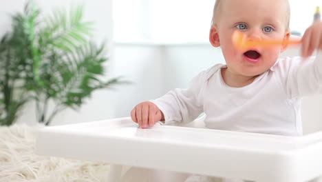 Baby-Sitzt-Und-Winkt-Mit-Orangefarbenem-Löffel