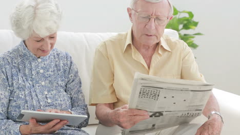 Pareja-De-Ancianos-Usando-Una-Tableta-Y-Un-Periódico