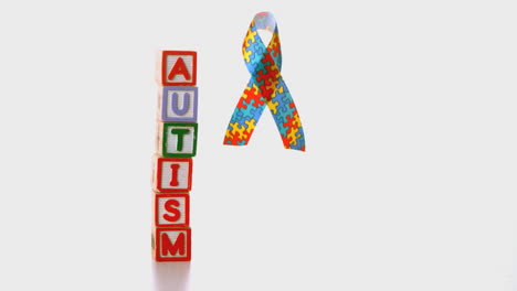 Awareness-ribbon-dropping-beside-blocks-spelling-autism