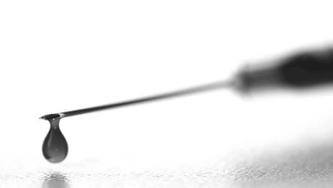 Drop-of-blood-falling-from-syringe-close-up-in-black-and-white