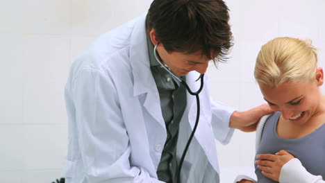 Médico-Varón-Auscultando-El-Vientre-Embarazado-De-Una-Paciente-Sonriente