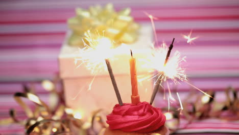 Wunderkerzen-Auf-Einem-Geburtstags-Cupcake-Mit-Geschenk