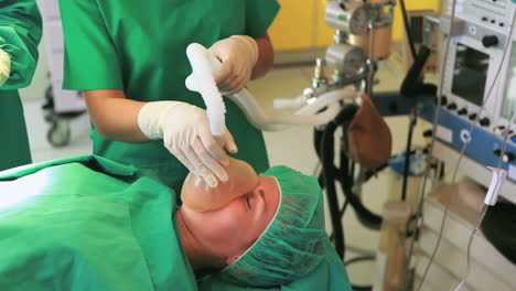 Sauerstoffmaske-Auf-Dem-Gesicht-Eines-Patienten-Platziert,-Während-Ein-Medizinisches-Team-Arbeitet