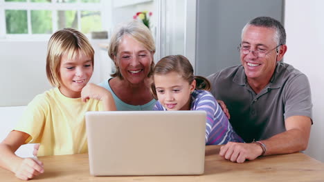 -Hermano-Y-Hermana-Mirando-Una-Computadora-Portátil-Con-Sus-Abuelos