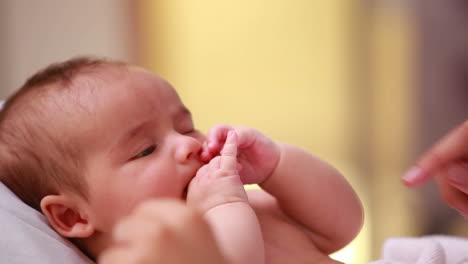 Neugeborenes-Baby-Liegt-Auf-Einem-Bett-Mit-Der-Hand-Eines-Erwachsenen