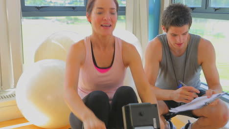 Happy-woman-at-the-rowing-machine-supporting-by-a-coach-