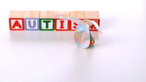 Awareness-ribbon-falling-in-front-of-autism-letter-blocks