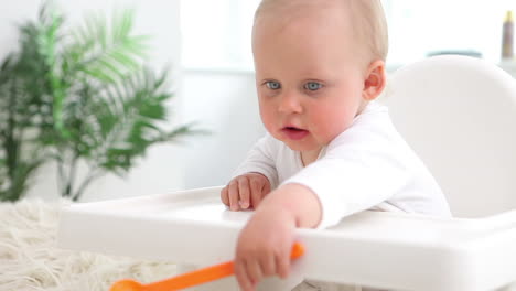 Baby-Sitzt-Und-Spielt-Mit-Orangefarbenem-Löffel