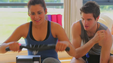Woman-at-the-rowing-machine-supporting-by-a-coach-