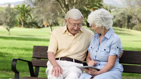 Old-couple-using-a-tablet-on-a-bench