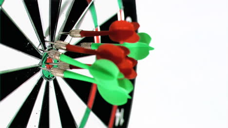 Green-and-red-darts-in-super-slow-motion-thrown-at-a-dart-board