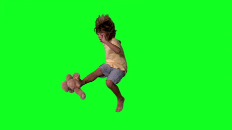 Little-boy-jumping-up-and-kicking-teddy-on-a-green-screen